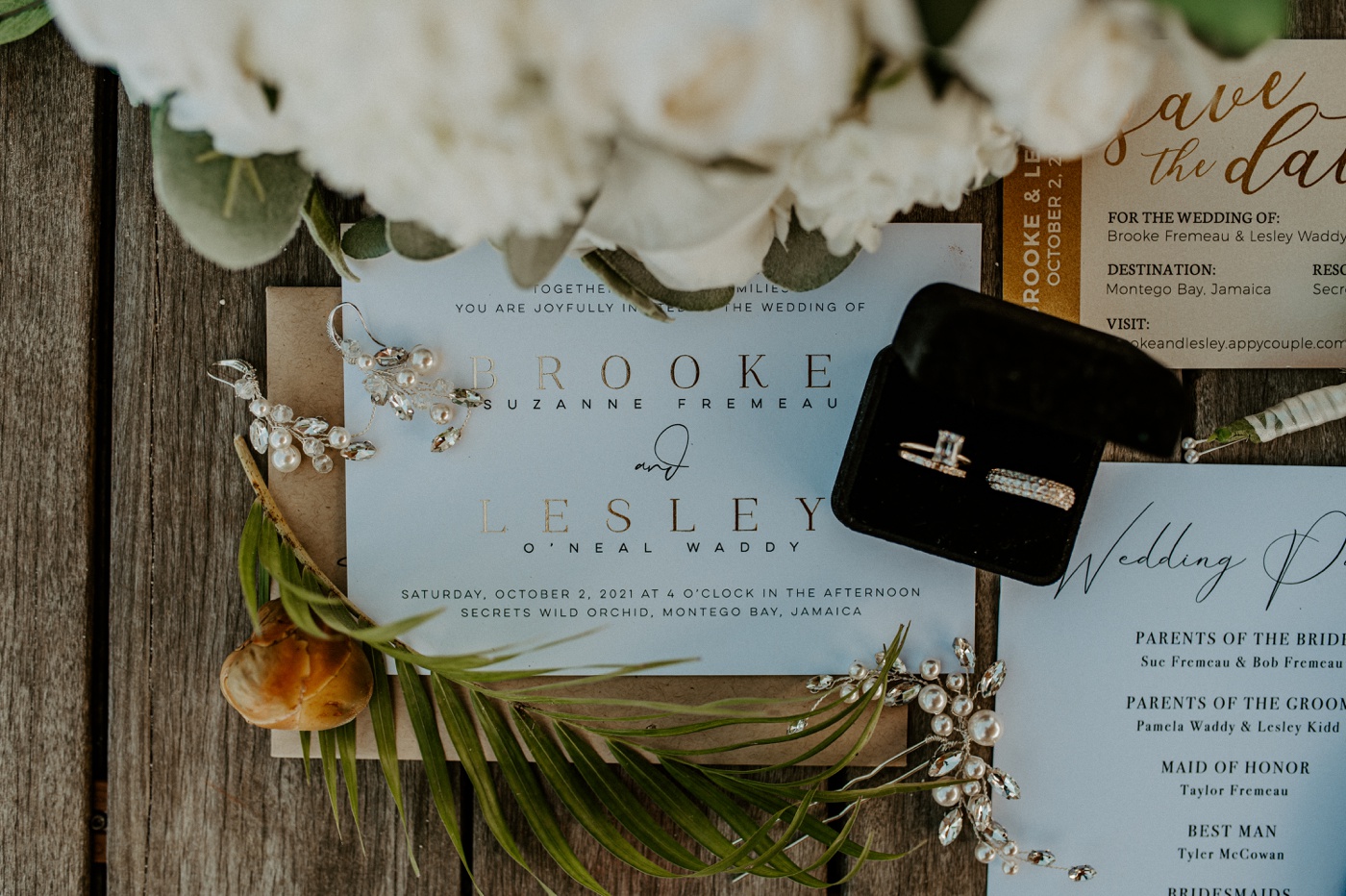Flat lay of a wedding invitation with a palm branch and white flowers