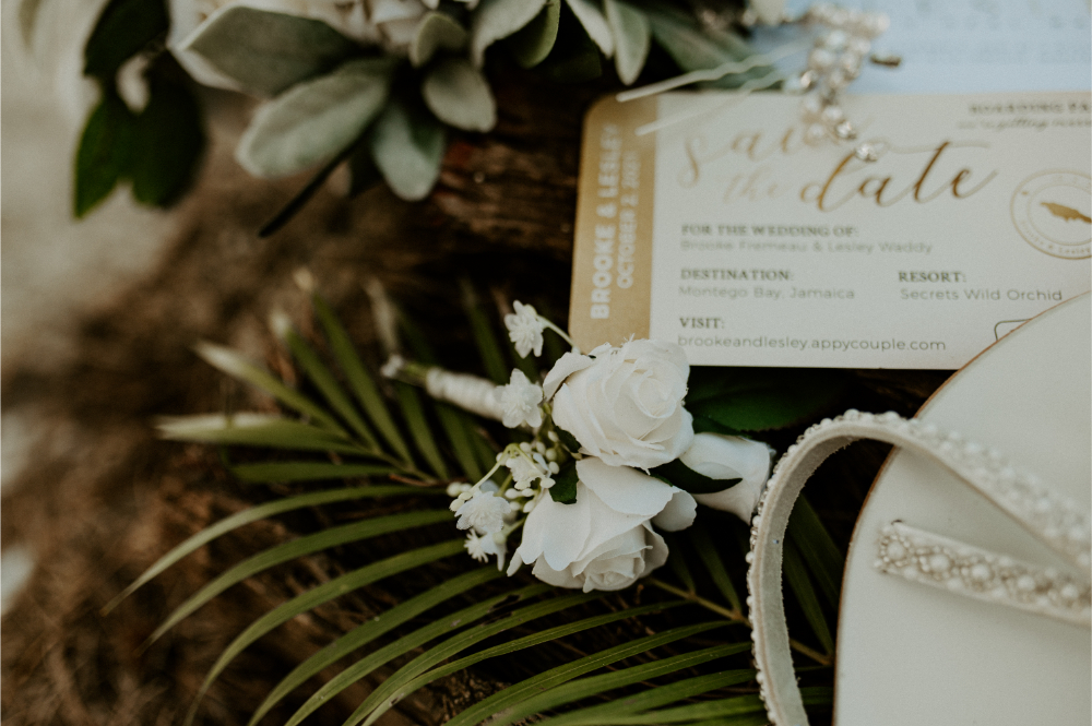 Destination wedding timeline details featuring wedding invitation, white flowers, and tropical greenery at resort wedding.