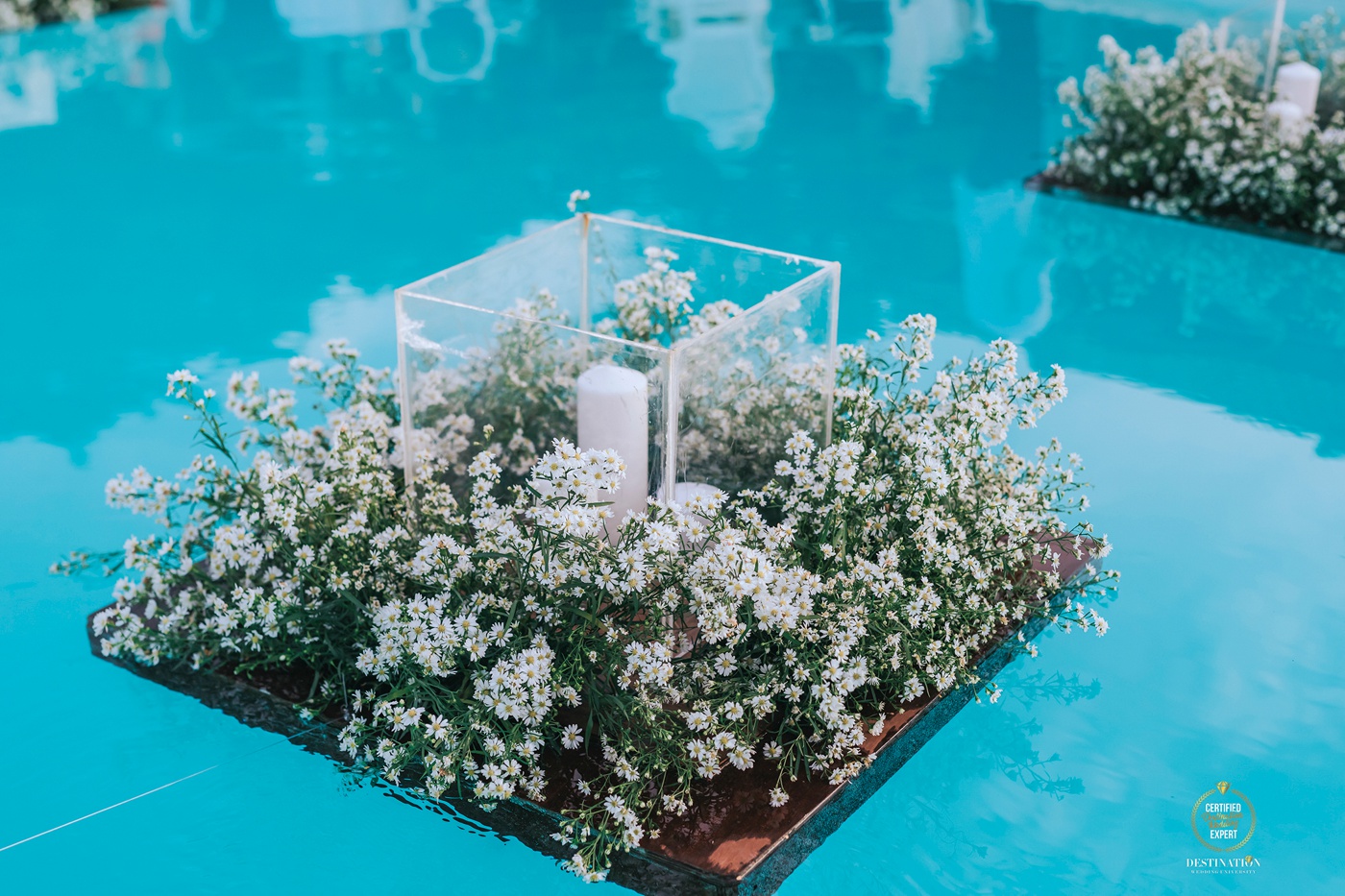 Floating floral installation with miniature mat daisies and candles at a destination wedding