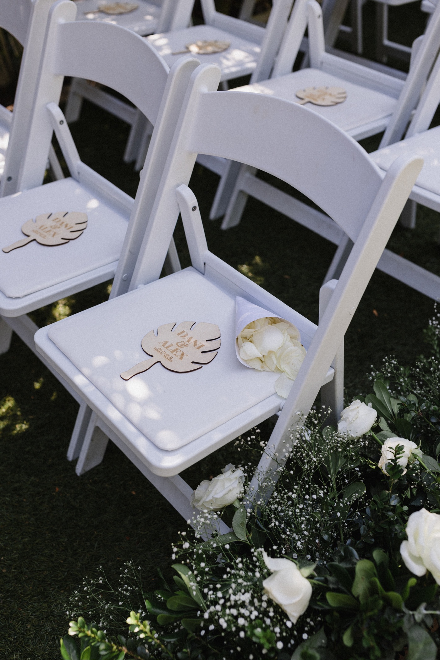 Custom wooden palm hand fans at an outdoor wedding ceremony