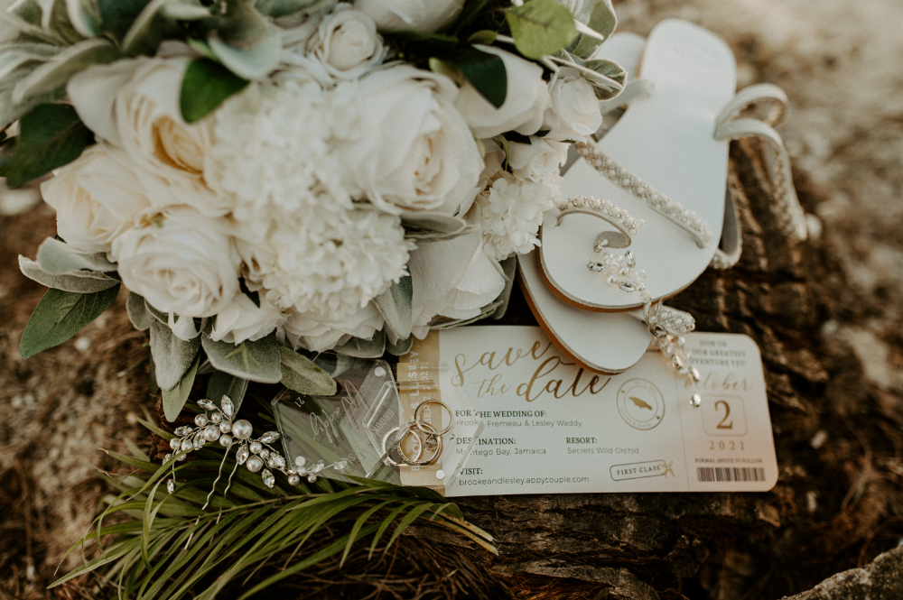 Wedding details with bouquet, rings, and invitation flat lay showing destination wedding cost and planning elements