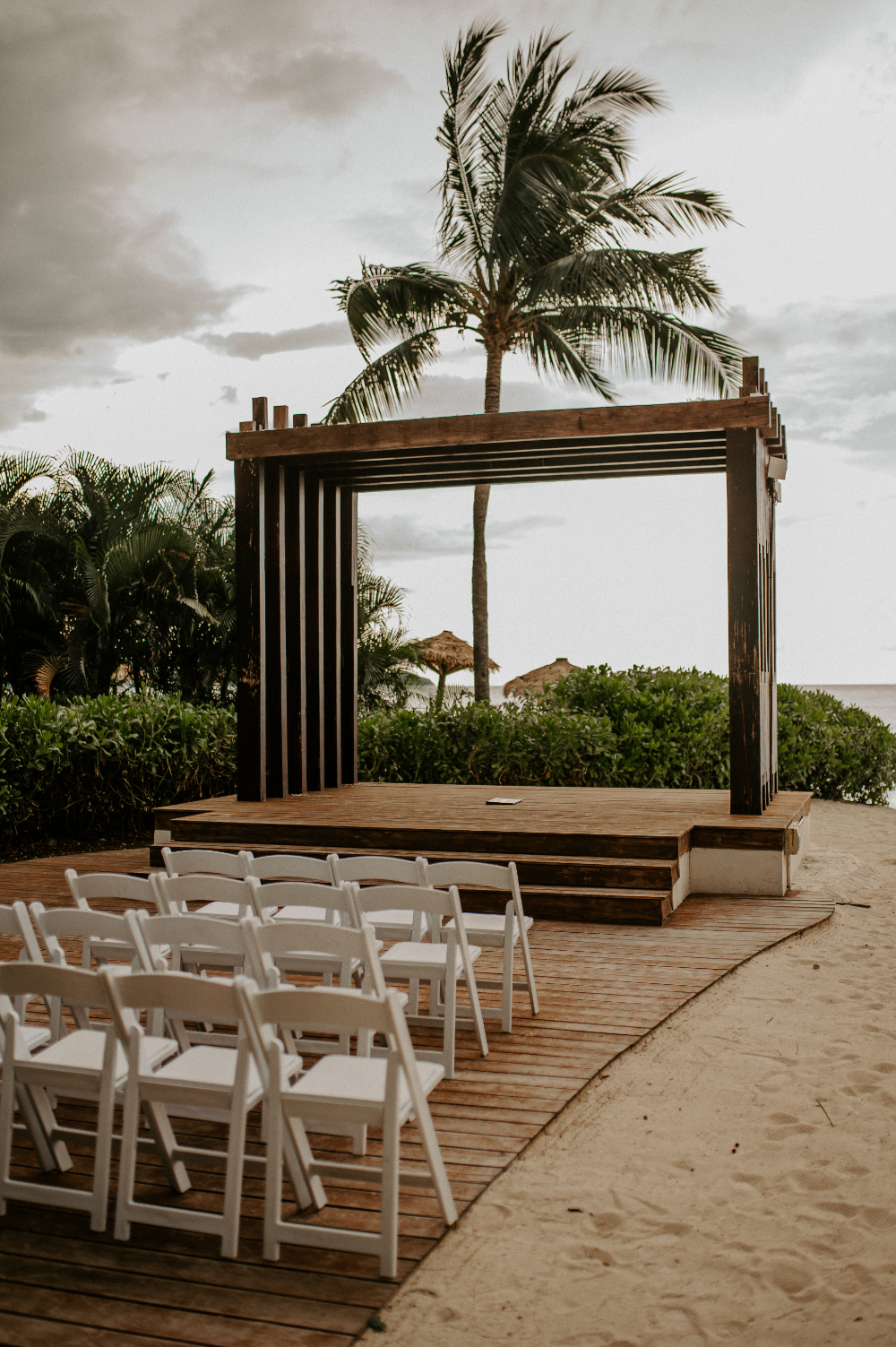 Beachfront ceremony setup with wooden arch, white chairs, and tropical setting reflecting destination wedding cost expectations