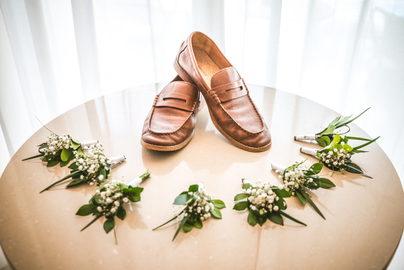 Groom shoes and boutonnières on table, destination wedding pros and cons detail styling shot