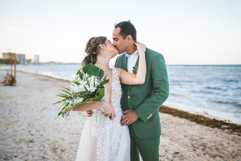 Bride and groom kissing on beach, romantic destination wedding pros and cons tropical ceremony moment