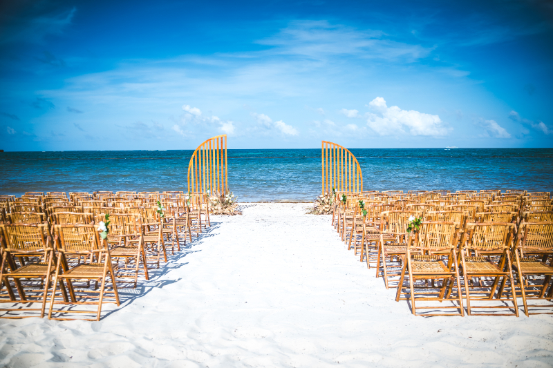 Beach ceremony setup with chairs facing ocean and simple arch on the sand