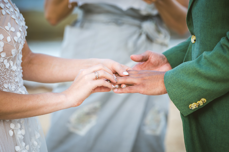 Close-up of ring exchange during ceremony with hands and wedding details