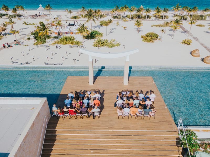 Just engaged destination wedding ceremony on oceanfront deck with guests seated overlooking beach and water
