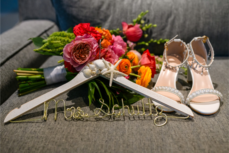 Destination wedding planner details featuring bridal bouquet, wedding shoes, and personalized wedding hangers.