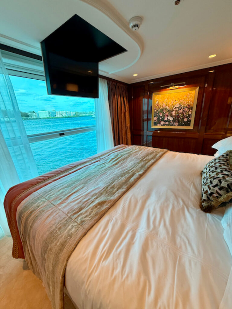 Spacious river cruise cabin with large window view, plush bedding, and elegant seating area