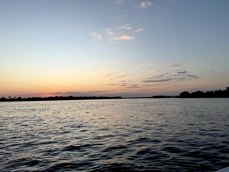 Peaceful sunset over calm water during an evening boat ride surrounded by natural coastal scenery.