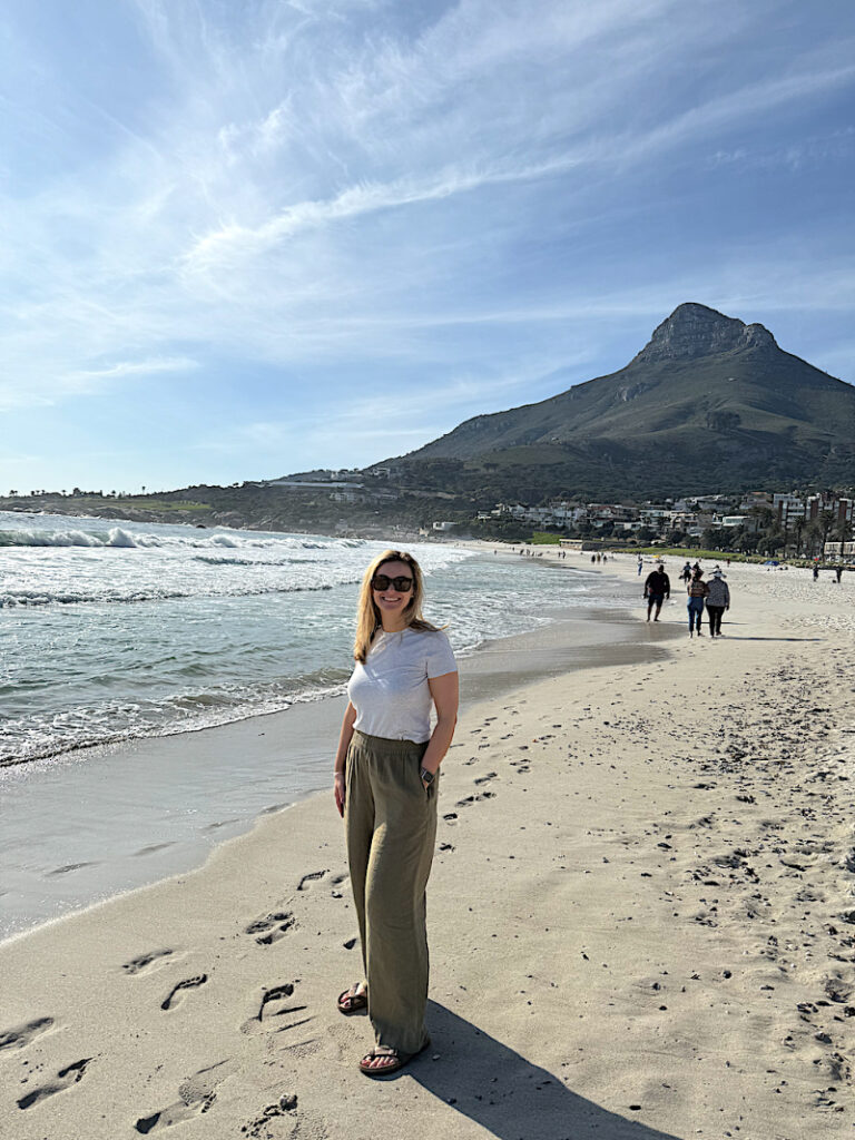 Woman walking along a Cape Town beach during a relaxing safari honeymoon and beach getaway in Africa.