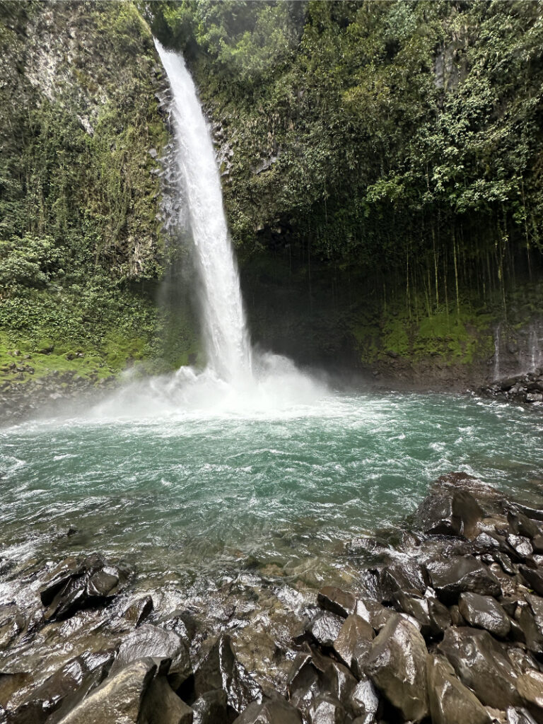 Waterfall cascading into a turquoise pool, one of the highlights when deciding where to go in Costa Rica.