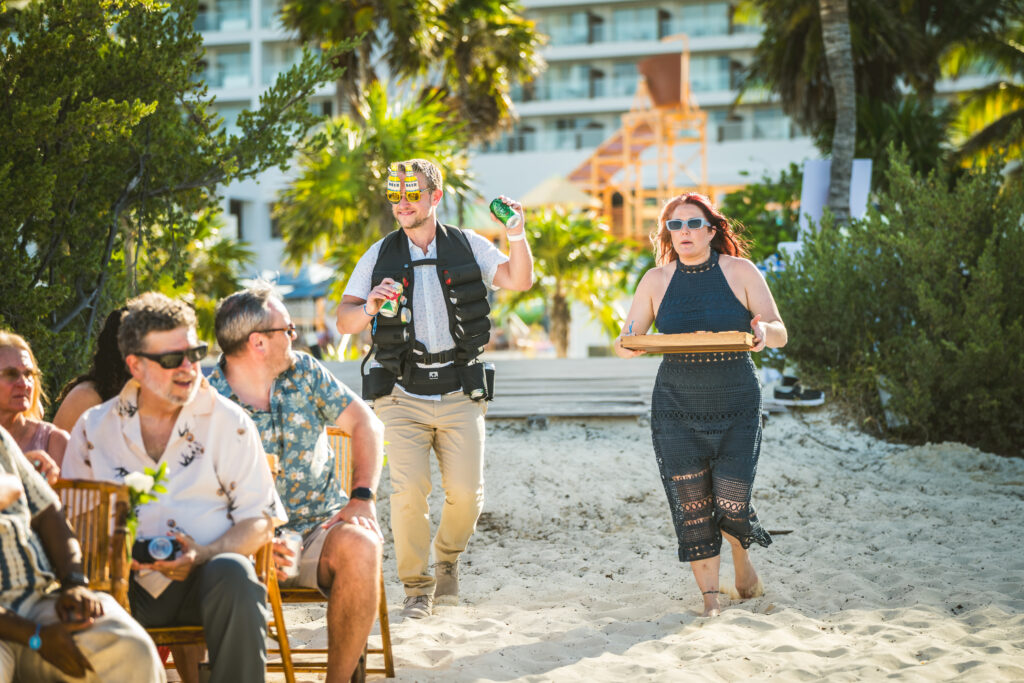 A beer boy and shot girl walking down aisle for a wedding ceremony at Royalton Splash Riviera Cancun.